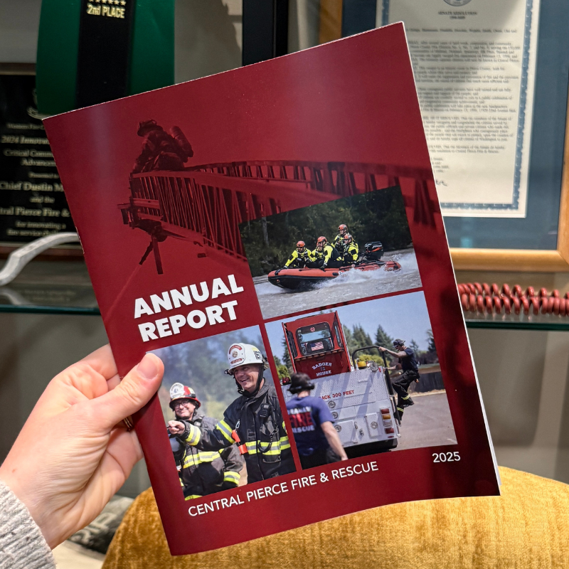 A hand holds a 2025 Central Pierce Fire & Rescue annual report with images of firefighters in action on the cover.